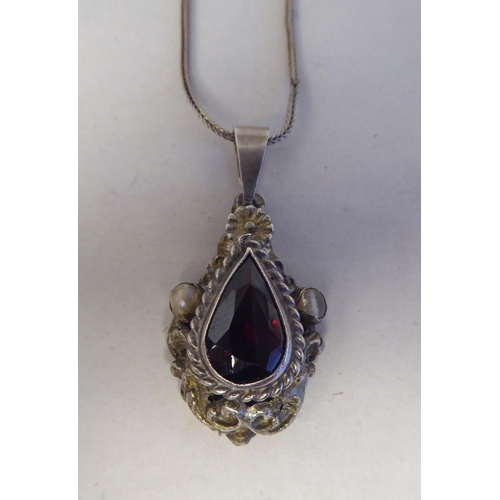 198 - A white metal pendant, set with a raised teardrop cut garnet, on a white metal chain  stamped 8... 