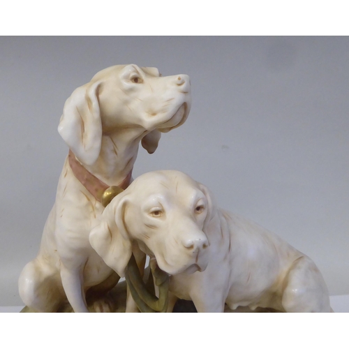 20 - A Royal Dux porcelain model, a pair of seated hounds, on an oval, naturalistically moulded plinth, i... 