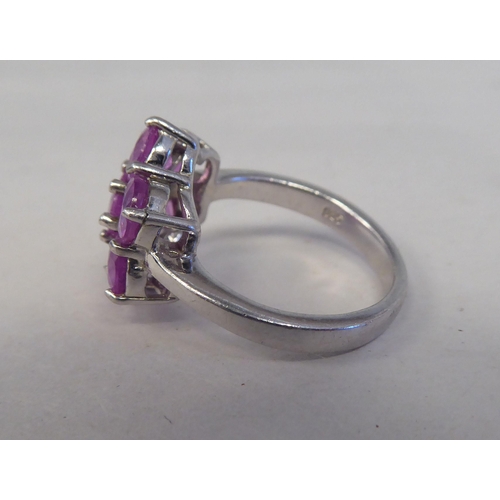 201 - A white metal cluster ring, set with seven pink sapphires  stamped 925 