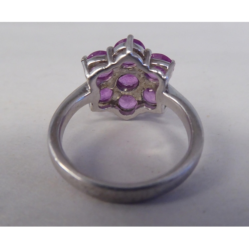 201 - A white metal cluster ring, set with seven pink sapphires  stamped 925 