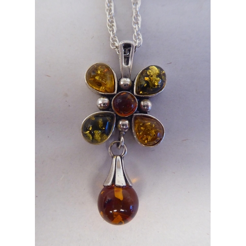 202 - A white metal pendant, fashioned as a cross, set with amber coloured beads, on a white metal necklac... 