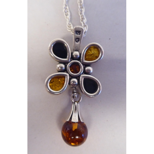 202 - A white metal pendant, fashioned as a cross, set with amber coloured beads, on a white metal necklac... 