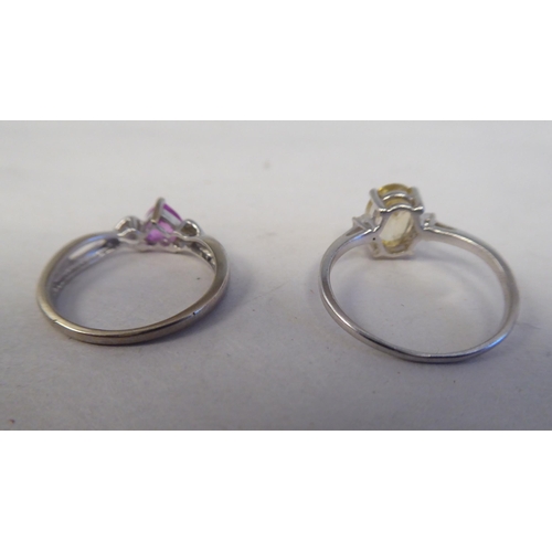 204 - Two white metal rings, one set with a yellow citrine, the other with a pink heart shaped stone 