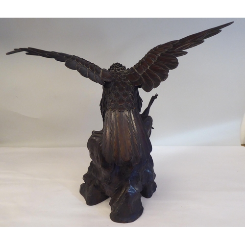 208 - A cast and patinated bronze model eagle, on a rock with captured prey  16