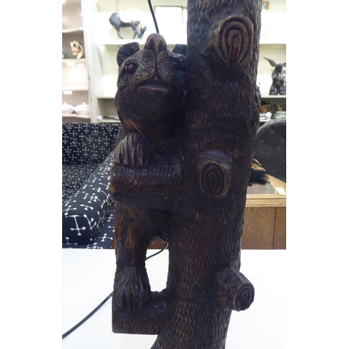 215 - A mid 20thC carved Black Forest table lamp, fashioned as a bear climbing a tree  24