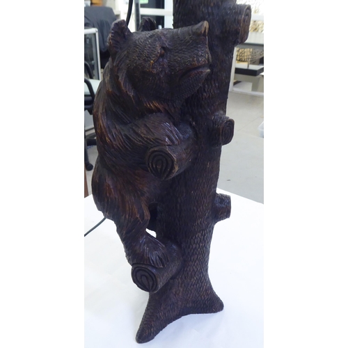 215 - A mid 20thC carved Black Forest table lamp, fashioned as a bear climbing a tree  24