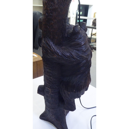 215 - A mid 20thC carved Black Forest table lamp, fashioned as a bear climbing a tree  24