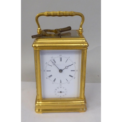 34 - An early 20thC French lacquered brass cased carriage clock with a folding top handle and bevelled gl... 