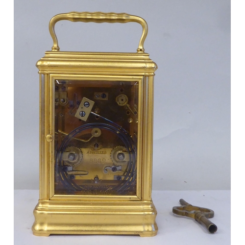 34 - An early 20thC French lacquered brass cased carriage clock with a folding top handle and bevelled gl... 