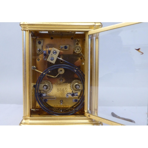 34 - An early 20thC French lacquered brass cased carriage clock with a folding top handle and bevelled gl... 