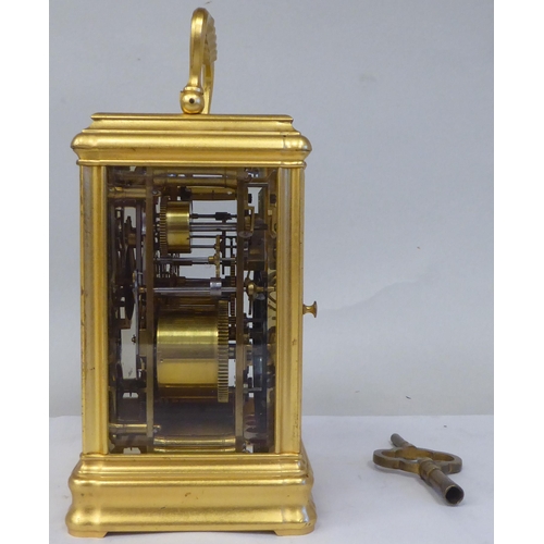 34 - An early 20thC French lacquered brass cased carriage clock with a folding top handle and bevelled gl... 