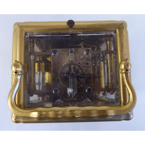 34 - An early 20thC French lacquered brass cased carriage clock with a folding top handle and bevelled gl... 