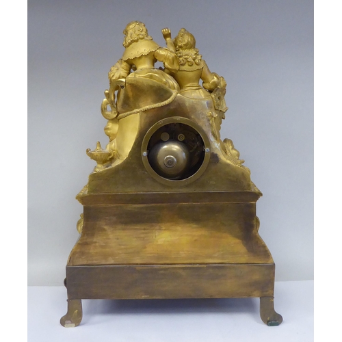 42 - A 19thC French gilt metal cased mantel clock, featuring a seated couple, on a draped cushion, the de... 