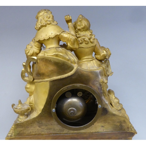 42 - A 19thC French gilt metal cased mantel clock, featuring a seated couple, on a draped cushion, the de... 