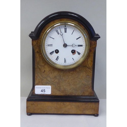 45 - An early 20thC part lacquered walnut cased mantel clock with a round arch top and flank windows, on ... 