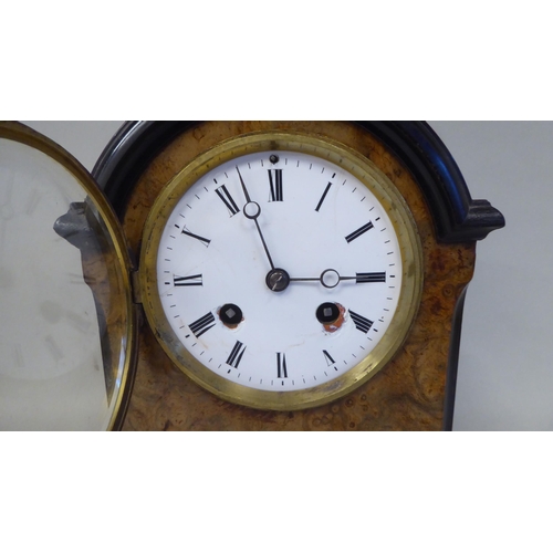 45 - An early 20thC part lacquered walnut cased mantel clock with a round arch top and flank windows, on ... 