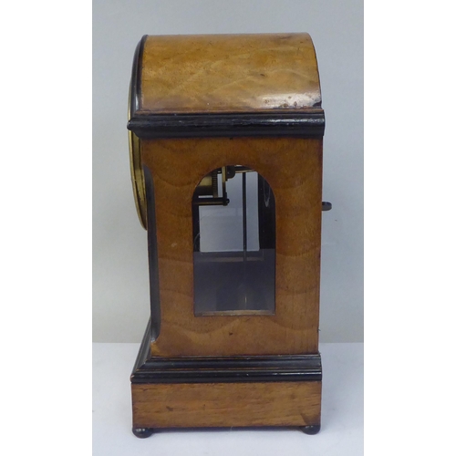 45 - An early 20thC part lacquered walnut cased mantel clock with a round arch top and flank windows, on ... 