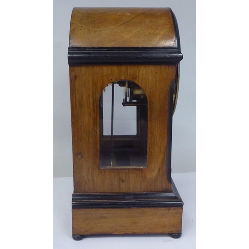 45 - An early 20thC part lacquered walnut cased mantel clock with a round arch top and flank windows, on ... 