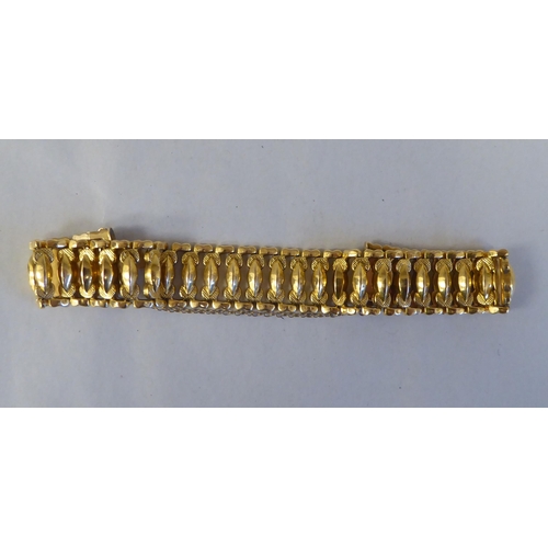 52 - An 18ct gold wide, flexible and engraved, open link bracelet, on a bayonet clasp with safety chain