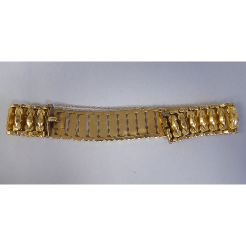 52 - An 18ct gold wide, flexible and engraved, open link bracelet, on a bayonet clasp with safety chain