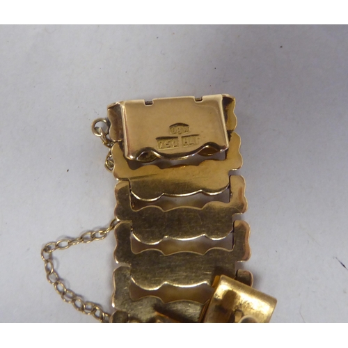 52 - An 18ct gold wide, flexible and engraved, open link bracelet, on a bayonet clasp with safety chain