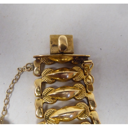 52 - An 18ct gold wide, flexible and engraved, open link bracelet, on a bayonet clasp with safety chain