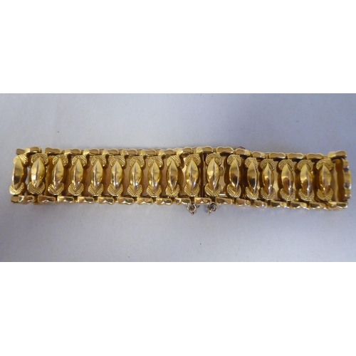 52 - An 18ct gold wide, flexible and engraved, open link bracelet, on a bayonet clasp with safety chain