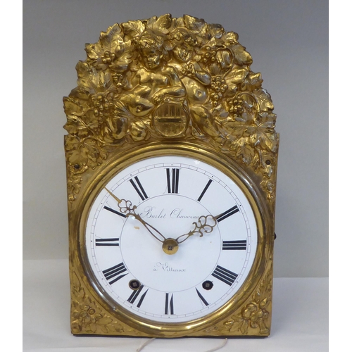 54 - A 19thC French Comptoise clock, faced by an elaborately pressed backplate, incorporating cherubic fi... 