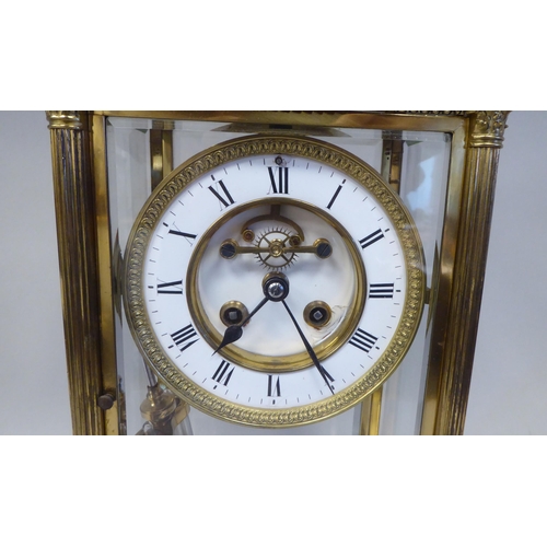 57 - A late Victorian lacquered brass, four glass mantel clock with bevelled panels; the visible bell str... 