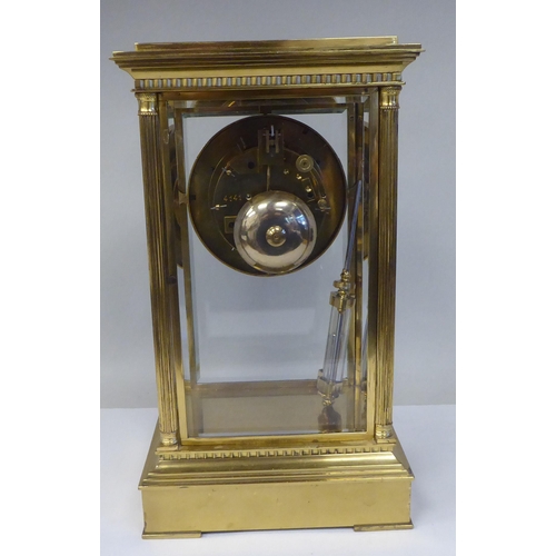 57 - A late Victorian lacquered brass, four glass mantel clock with bevelled panels; the visible bell str... 