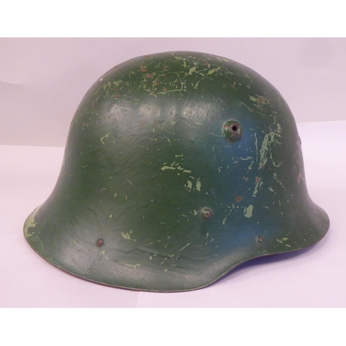 63 - A military design painted steel helmet with a hide liner and buckled chinstrap(Please Note: this lot... 