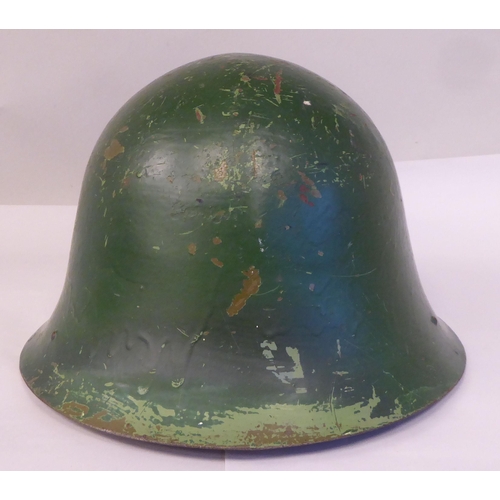 63 - A military design painted steel helmet with a hide liner and buckled chinstrap(Please Note: this lot... 