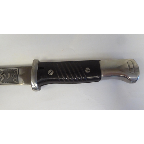 64 - A German World War II military bayonet with a two-part handgrip, the engraved blade 9.5