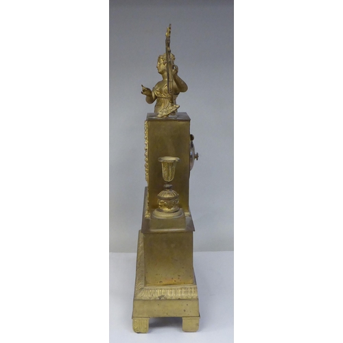 65 - A late 19thC Continental gilded metal cased mantel clock, ornamented with a standing classical maide... 