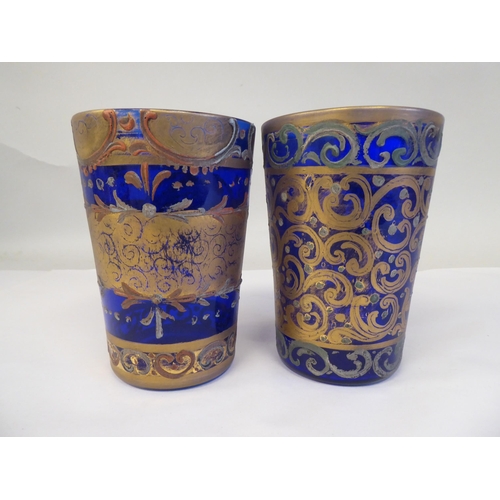 66 - A pair of 19thC Continental blue glass beakers of tapered form, similarly overpainted and gilded wit... 