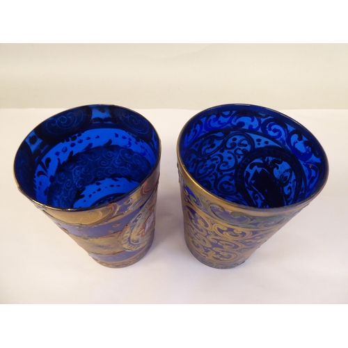 66 - A pair of 19thC Continental blue glass beakers of tapered form, similarly overpainted and gilded wit... 