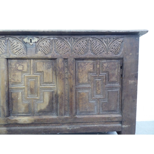 77 - A 17thC boarded oak coffer with a tri-panelled front, incorporating lunette and foliate carved ornam... 