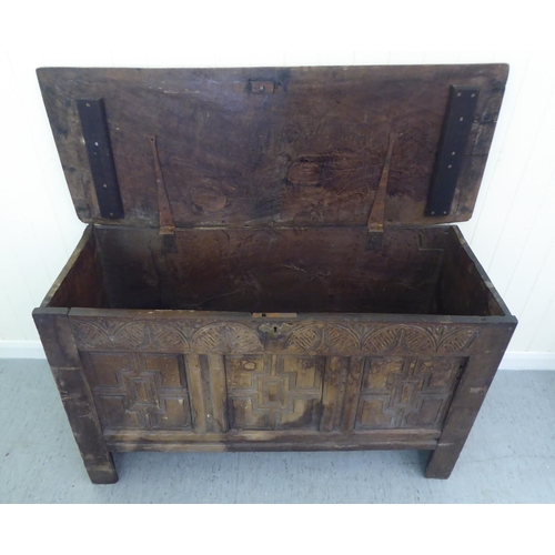 77 - A 17thC boarded oak coffer with a tri-panelled front, incorporating lunette and foliate carved ornam... 