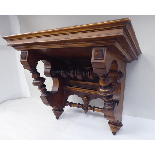 95 - A late Victorian walnut clock bracket, the platform top over a series of elaborately turned supports... 