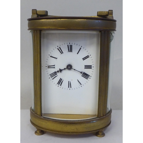 23 - An early 20thC French oval brass cased carriage timepiece with bevelled glass panels and a folding t... 