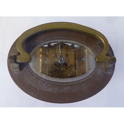 23 - An early 20thC French oval brass cased carriage timepiece with bevelled glass panels and a folding t... 