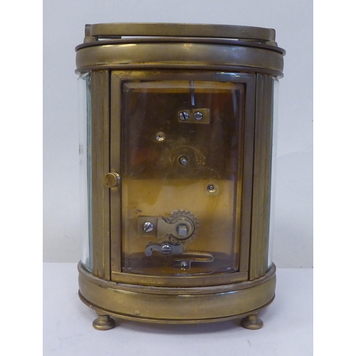 23 - An early 20thC French oval brass cased carriage timepiece with bevelled glass panels and a folding t... 