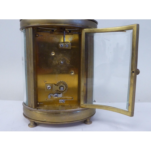 23 - An early 20thC French oval brass cased carriage timepiece with bevelled glass panels and a folding t... 