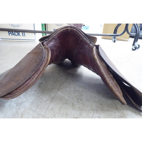 134 - Two brown hide horse saddles; and another in black hide