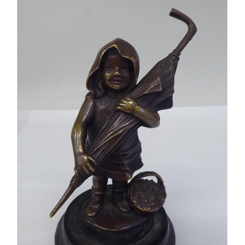 145 - A cast and patinated bronze figure, a little girl carrying an adult's umbrella, on a turned wooden p... 