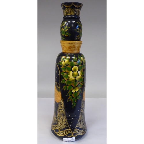 222 - A Russian turned and painted softwood bottle vase, featuring a young woman wearing traditional costu... 