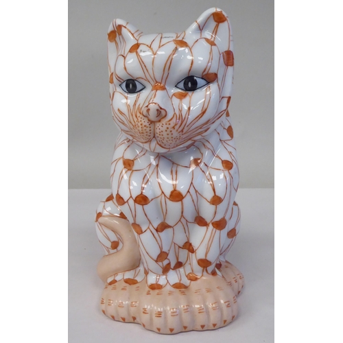 231 - A 20thC porcelain model, a seated cat, decorated in iron red with blue eyes  6.75