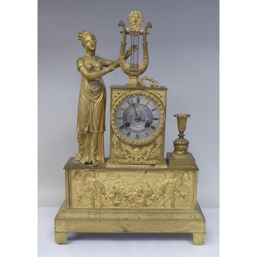 293 - A late 19thC Continental gilded metal cased mantel clock, ornamented with a standing classical maide... 