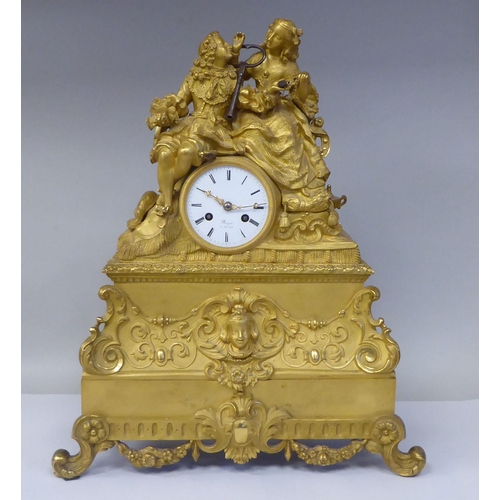 308 - A 19thC French gilt metal cased mantel clock, featuring a seated couple, on a draped cushion, the de... 