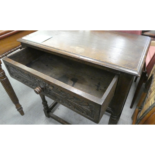 22 - An early 20thC Jacobean style, oak single drawer side table, raised on turned and block legs  3... 